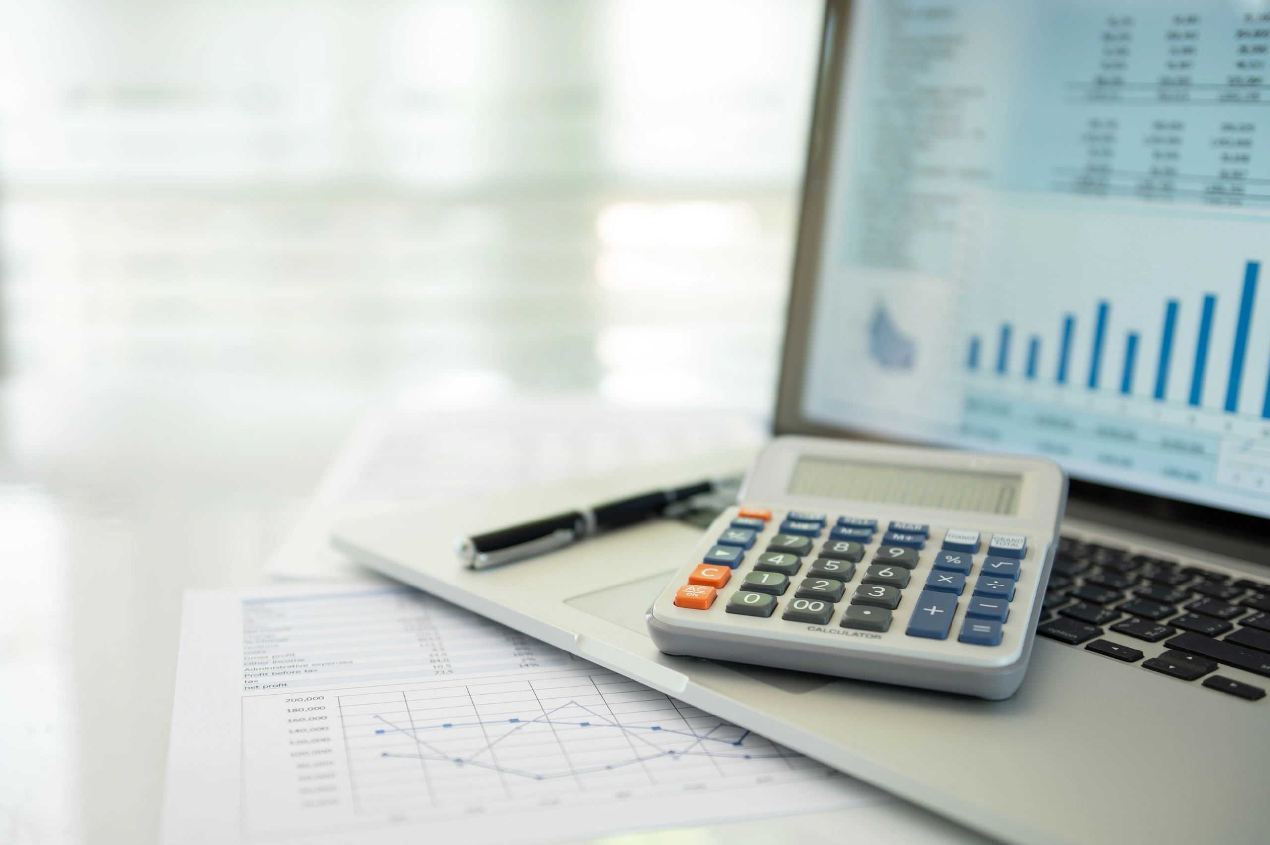 Laptop with financial reports, calculator, and accounting documents on a desk